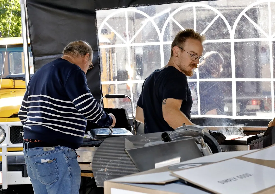 2 mannen zijn bezig aan het barbecuen op de jaarmarkt van Rode